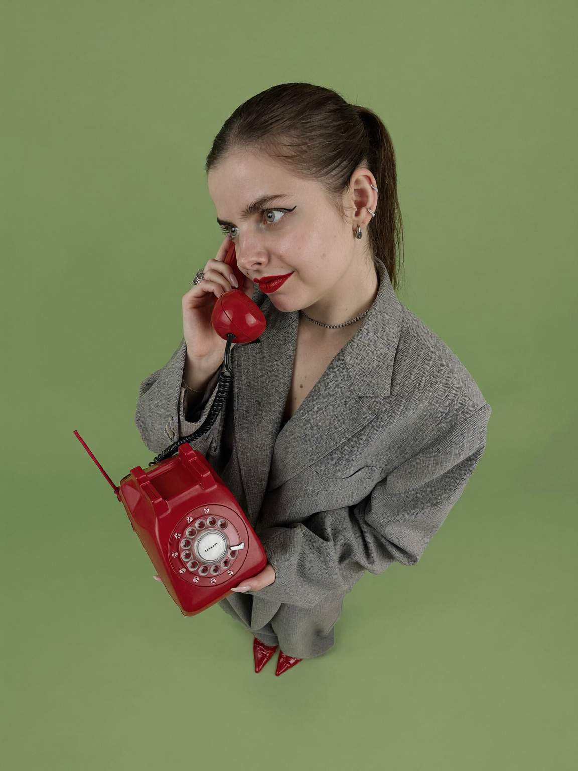 Michelle Telemann mit einem roten Wählscheibentelefon vor grünem Hintergrund.